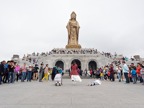 Putuoshan, CHINA - May 2, 2015: Three young ladies pray south sea Guanyin and crowded people watching.