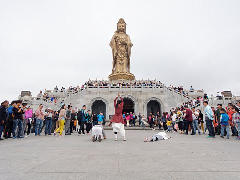 Putuoshan, CHINA - May 2, 2015: Three young ladies pray south sea Guanyin and crowded people watching.