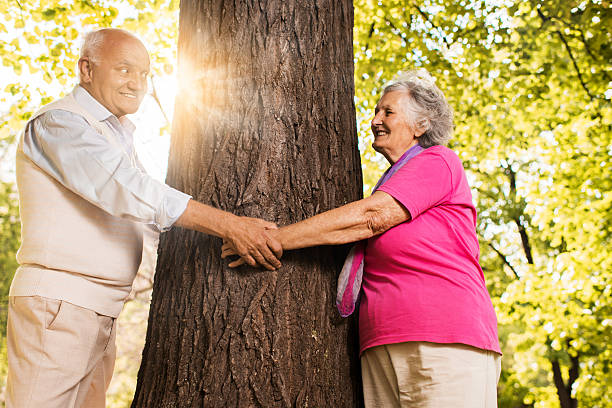 istock Happy elderly couple holding hands around the tree in nature. 489489254