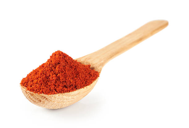 Paprika on a wooden spoon isolated on white background. Macro.