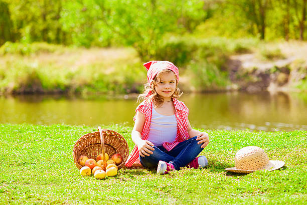 Little girl in jeans and a shirt near a river in autumn stock photo