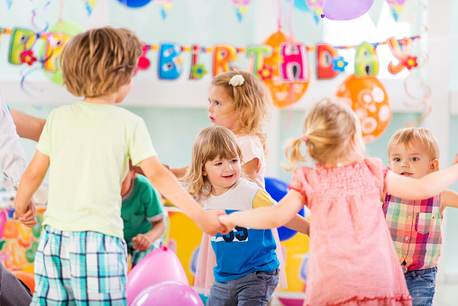 Group of children enjoying and playing ring around the rosy on a birthday party.
