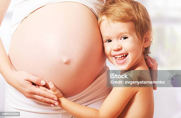 Happy Family Child Hugs Belly Of Pregnant Mother Stock Photo - Download Image Now - Human Abdomen, Mother, 2015