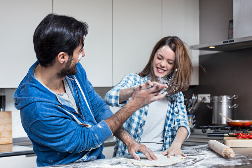 Playful couple throwing flour each other in the kitchen.
