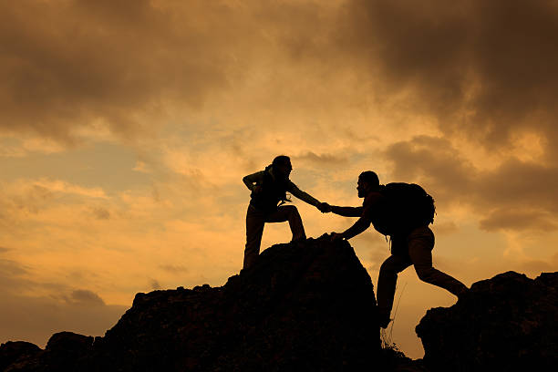 istock Man and woman help silhouette in mountains 489516138