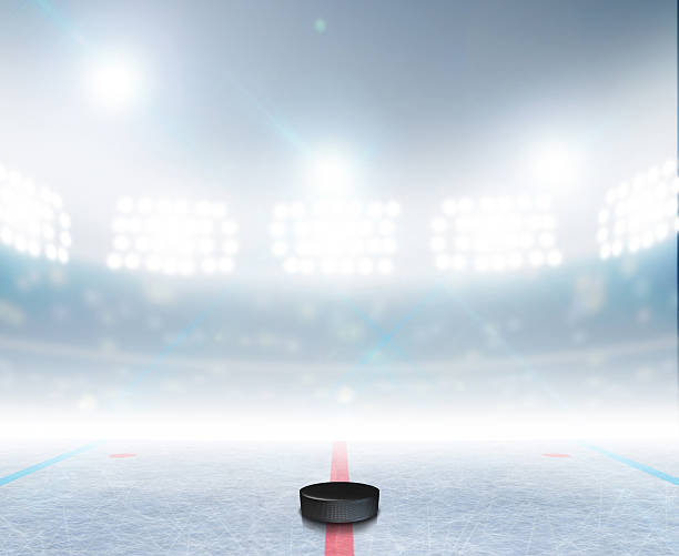 Ice Hockey Rink Stadium A generic ice hockey ice rink stadium with a frozen surface and a hockey puck under illuminated floodlights hockey puck photos stock pictures, royalty-free photos & images