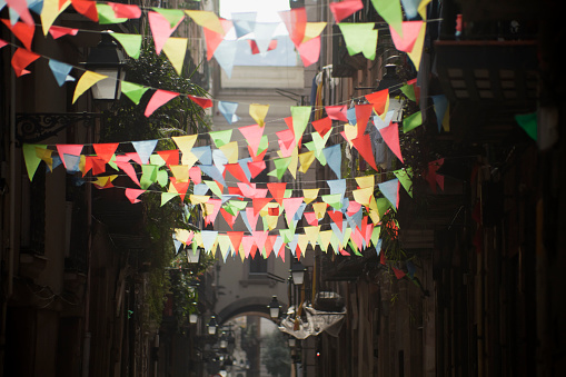 Multicolored feast decorations backlit  in a narrow street.