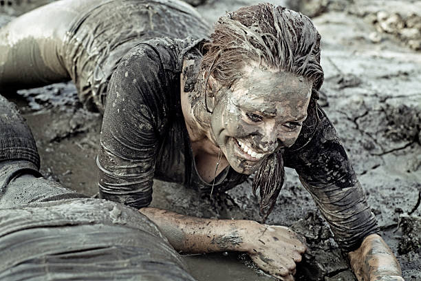 istock Young brunette female crawling during a mud run 489521136