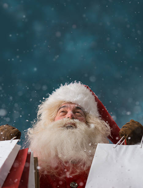 istock Santa Claus outdoors in snowfall holding shopping bags 489523976