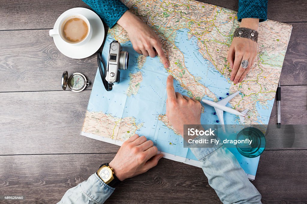 couple planning honeymoon Young couple planning honeymoon vacation trip with map. Top view. Pointing to Europe Rome Travel Stock Photo