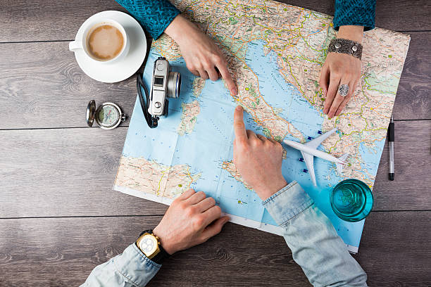couple planning honeymoon Young couple planning honeymoon vacation trip with map. Top view. Pointing to Europe Rome navigational compass photos stock pictures, royalty-free photos & images