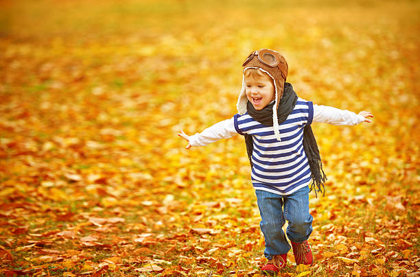 niño feliz jugando al aire libre en otoño piloto de piloto - running down fotografías e imágenes de stock