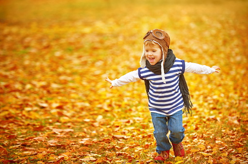 happy child playing pilot aviator and dreams outdoors in autumn