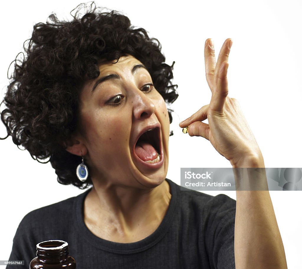 Woman swallows a pill Woman is holding a pill and her mouth wide open to swallow it Capsule - Medicine Stock Photo