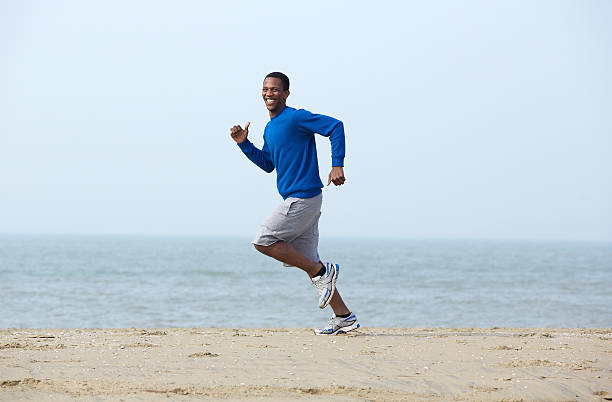 istock Smiling man jogging at the beach 489548851