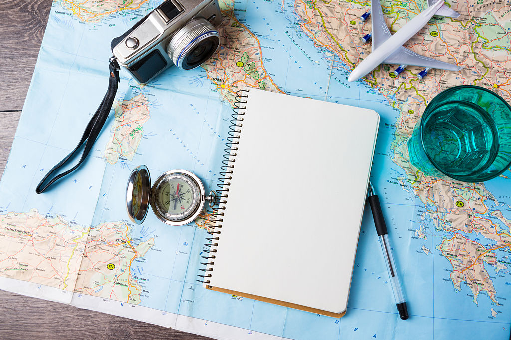 Reisetourismusbüro Tisch Mockup Tools Kompass, Glas Wasser Notizblock, Stift und Spielzeug Flugzeug und touristische Karte auf Holztisch. Leeren Raum können Sie Ihren Text oder Ihre Informationen platzieren.