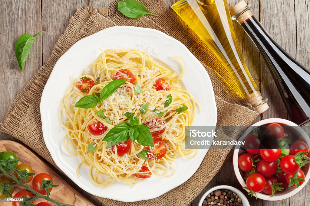 Spaghetti pasta with tomatoes and basil Spaghetti pasta with tomatoes and basil on wooden table. Top view 2015 Stock Photo