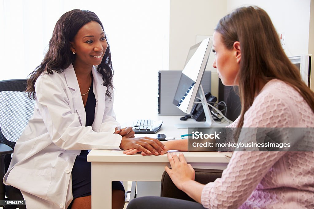 Female Doctor Treating Patient Suffering With Depression Holding Hands Stock Photo