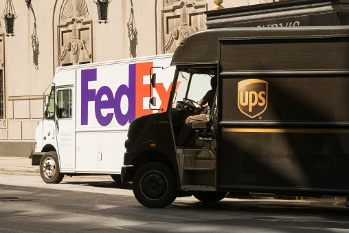 Chicago, USA - September 11, 2015: A UPS delivery truck passing a FedEx truck on Michigan Avenue in the Loop late in the day in front of Lawrys.