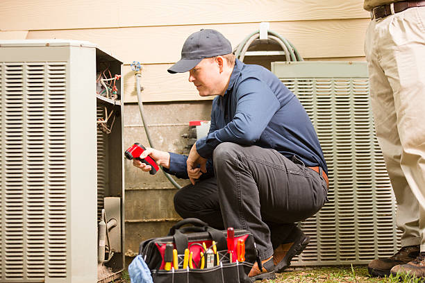 Air conditioner repairmen work on home unit. Blue collar workers. Mid-adult repairman works on a home's air conditioner unit outdoors. Man center is working on the unit using tools in his toolbox.  Other man to right. They both wear uniforms.  service occupation stock pictures, royalty-free photos & images