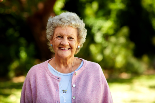 Portrait of happy senior woman in sweater at park