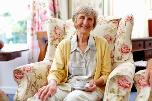 Portrait of happy senior woman with coffee cup in nursing home