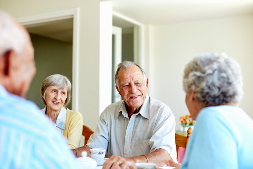 Happy senior people spending leisure time at table in nursing home