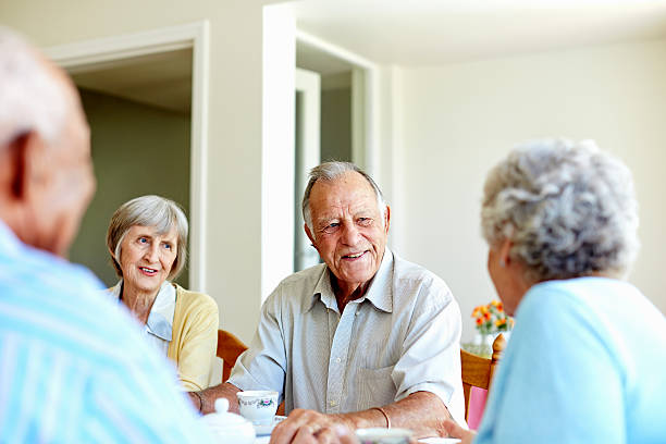 Seniors spending leisure time in nursing home Happy senior people spending leisure time at table in nursing home happiness four people cheerful senior adult stock pictures, royalty-free photos & images