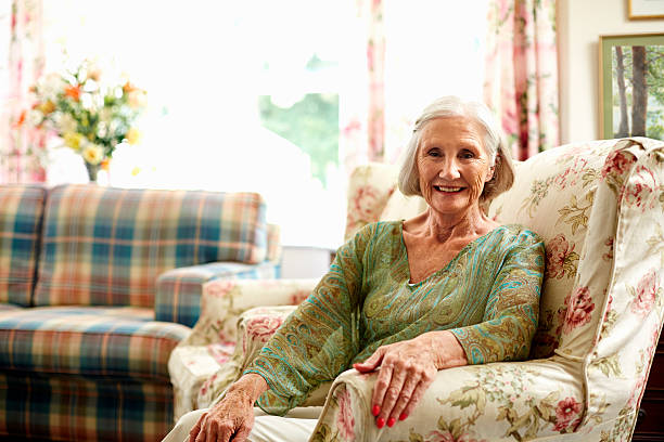 happy senior woman relaxing on armchair - nur seniorinnen stock-fotos und bilder