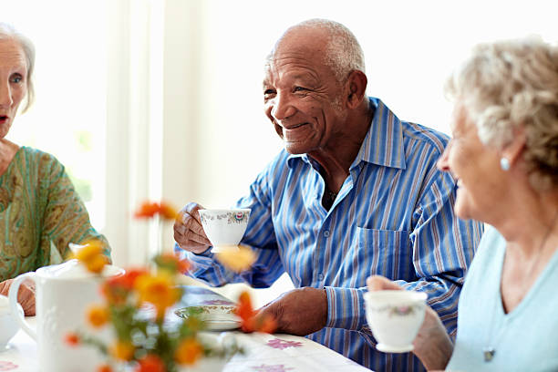 Senior man having coffee with friends Smiling senior man having coffee with friends in nursing home senior lifestyle stock pictures, royalty-free photos & images