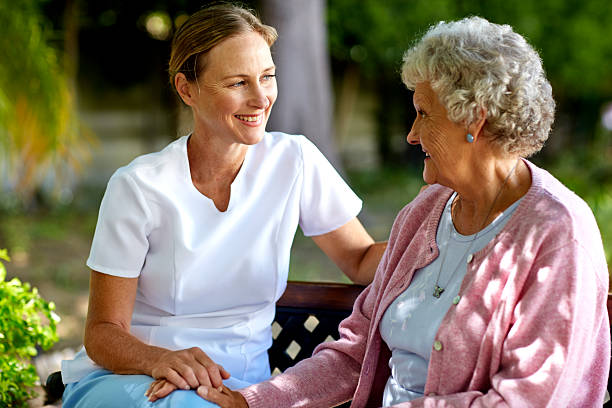 Happy caretaker and senior woman in park Happy female caretaker and senior woman looking at each other in park custodian stock pictures, royalty-free photos & images