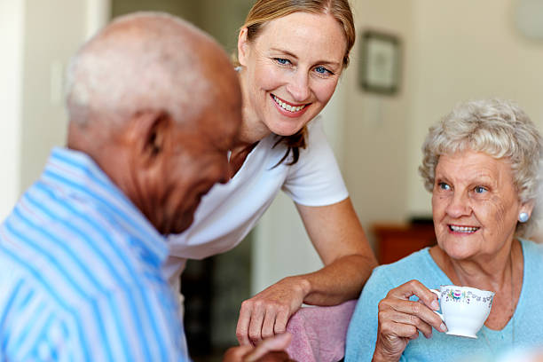 Caretaker with senior people in nursing home Happy female caretaker with senior people having coffee in nursing home retirement community stock pictures, royalty-free photos & images