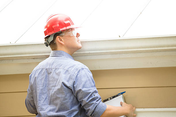 Inspector or blue collar worker examines building roof.  Outdoors. stock photo