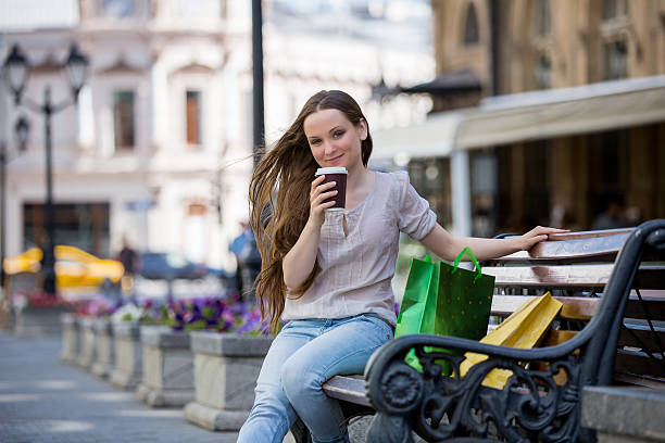 istock Young beautiful woman on a bench with coffee cup 489601212