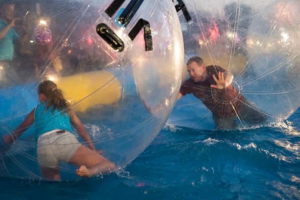Zorbing fun at county fair Two people roll around inside giant plastic balls floating in water on a summer evening at the county fair, Rochester, MN, USA zorb ball stock pictures, royalty-free photos & images