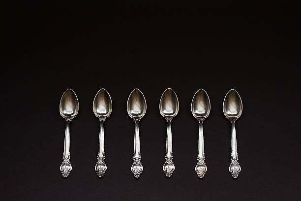 six silver spoons dans une rangée sur fond noir - upper class food empty retro revival photos et images de collection