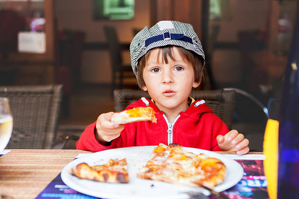 istock Sweet adorable child, boy, eating pizza at a restaurant 489610434