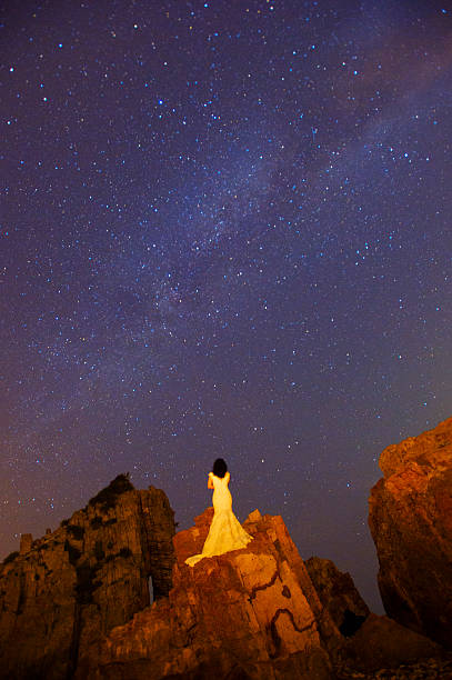 istock Woman standing in dress at night watching Galaxy 489612322