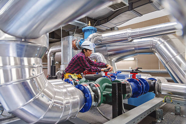 Technician working on valve in factory or utility In utility or factory one technician or engineers working on a valve on building technical equipment or industrial site piping hot stock pictures, royalty-free photos & images