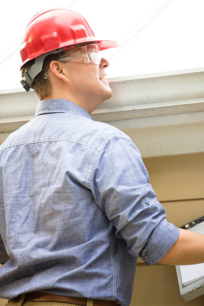 istock Inspector or blue collar worker examines building roof.  Outdoors. 489636084