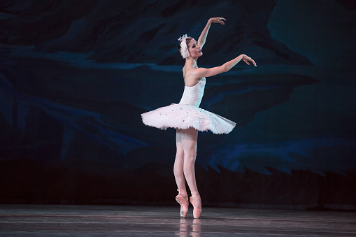 Young ballerina practicing dance moves on black background