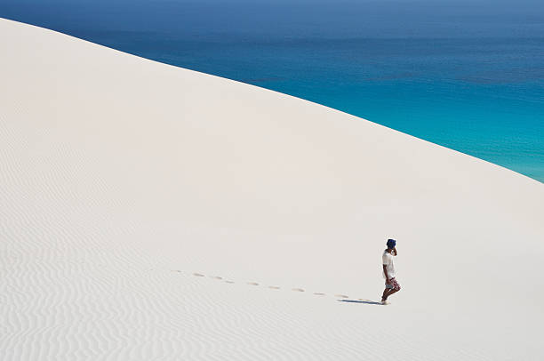 Socotra, Yemen, man walking in white dunes in Arher Socotra, Yemen, March, 26,2014. Yemeni scene: Man walking in white dunes in Arher sand river stock pictures, royalty-free photos & images