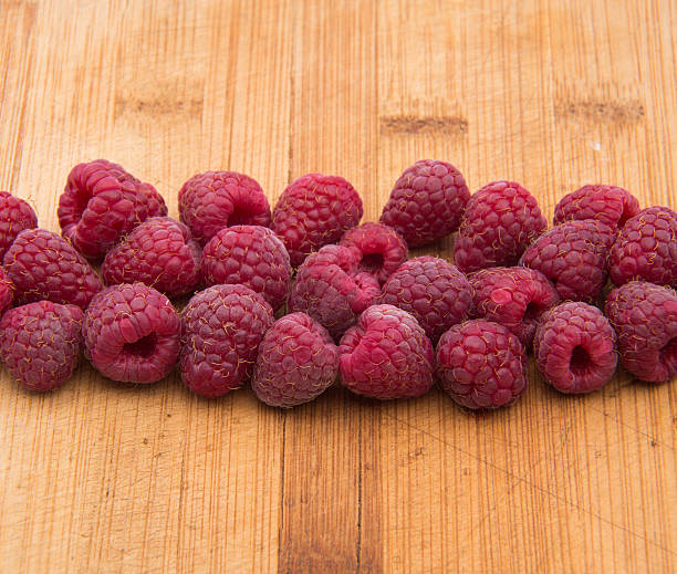 Ripe sweet raspberries on wood table close-up