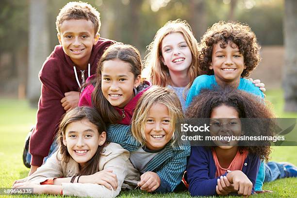 Group Of Children Lying On Grass Together In Park Stock Photo - Download Image Now - Child, Multiracial Group, Human Face