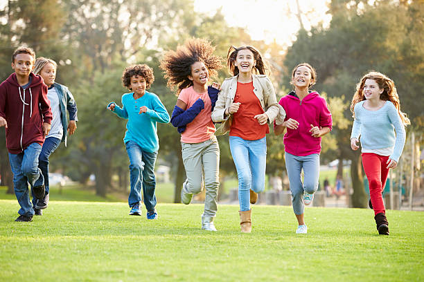 gruppo di bambini piccoli in esecuzione nel parco in direzione della telecamera - child playing running group of people foto e immagini stock