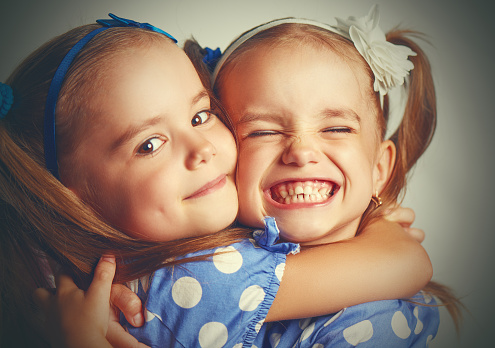 Couple of charming childs having fun outdoors. Portrait of beautiful girl and boy are hugging, smiling and looking at the camera. Little brother and sister in park on a green grass.