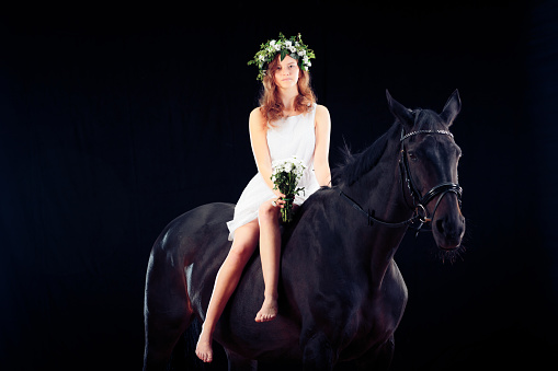 Young Girl With Her Horse, studio shot on black background.