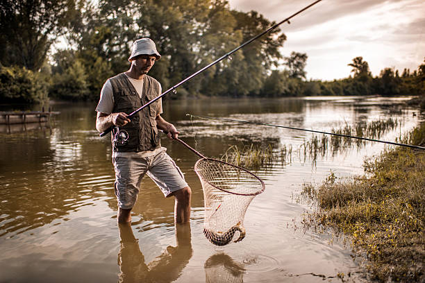 istock Fisherman with a fish in net going out of water. 489664506