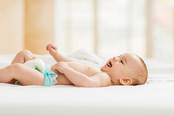 istock Cute baby lying down in bed and laughing. 489666380