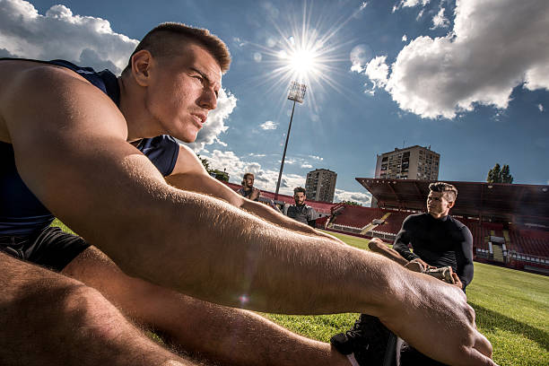 Young men stretching on a stadium before sports training.
